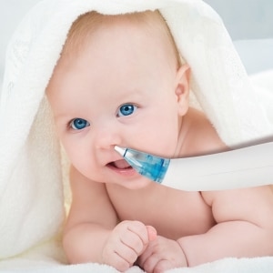 Un aspirateur nasal électrique avec un bébé et une serviette de bain