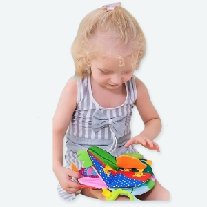 Livre en tissu doux avec un bébé qui joue avec et un fond bleu.