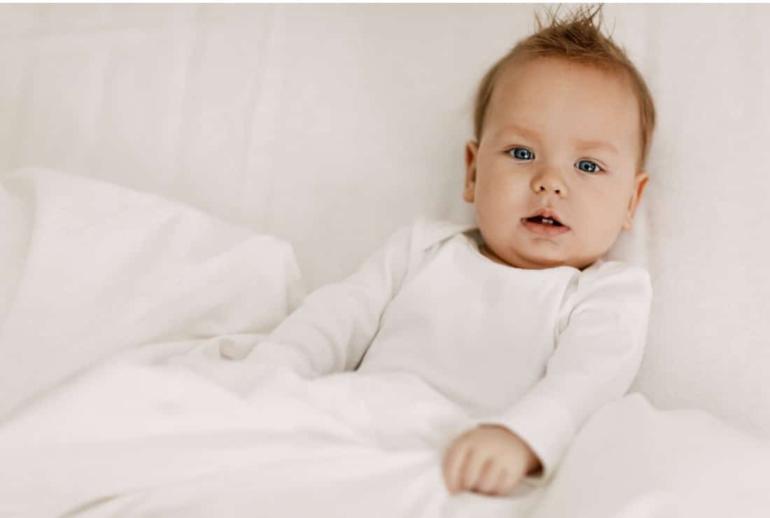 bébé dans son lit en body blanc 