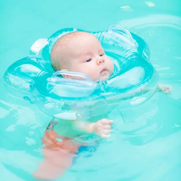 petit bébé nage avec l'aide de sa bouée à la piscine