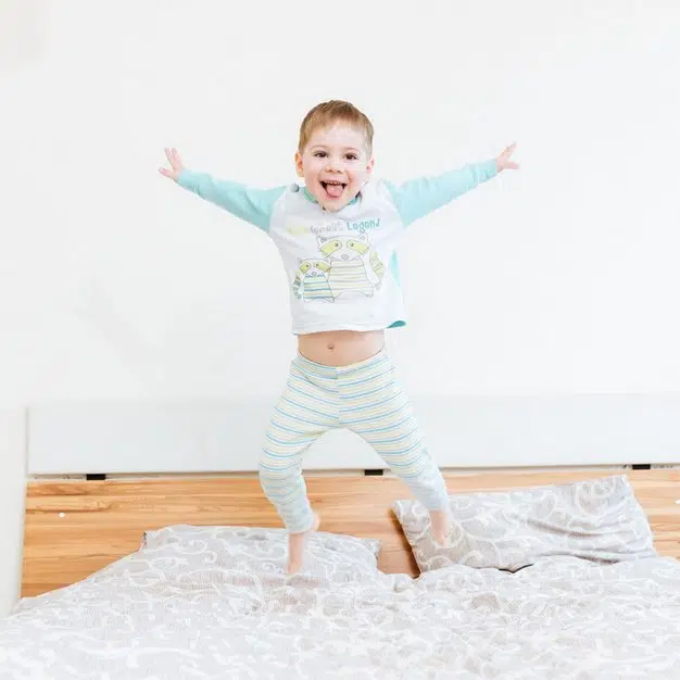 petit bébé heureux avec son pyjama et saute sur son lit