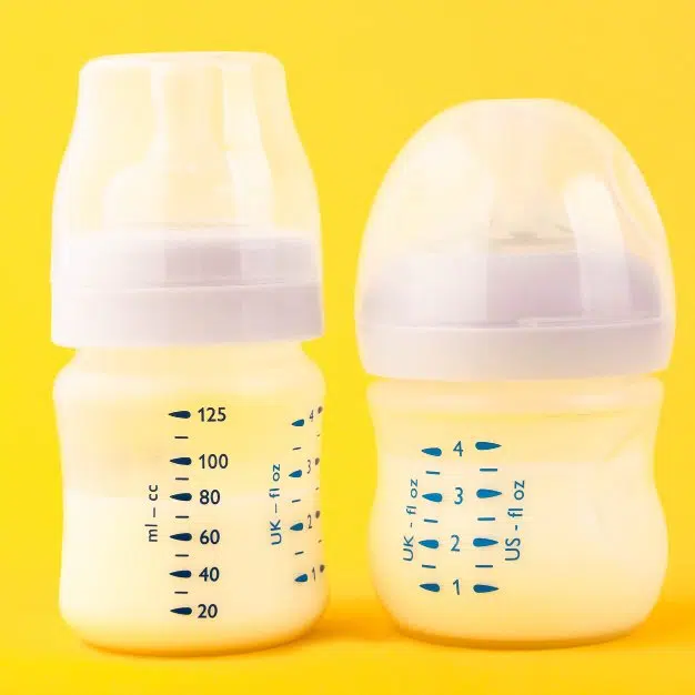 Deux biberons blancs pour bébé sur fond jaune