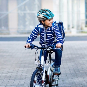 Joli casque de vélo de sécurité pour enfant avec un garçon qui fait du vélo avec le casque sur la tête
