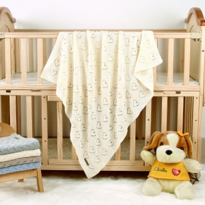 Couverture tricotée en coton pour bébé dans un lit de bébé avec une peluche par terre