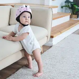 Casque de protection rose bébé avec un bébé qui le porte sur la tête