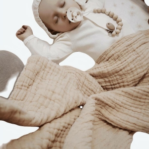Couverture pour bébé en mousseline biologique beige avec un bébé qui dort