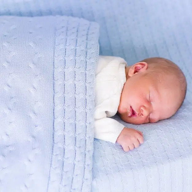Nouveau né qui dort couvert d'une couette bleue