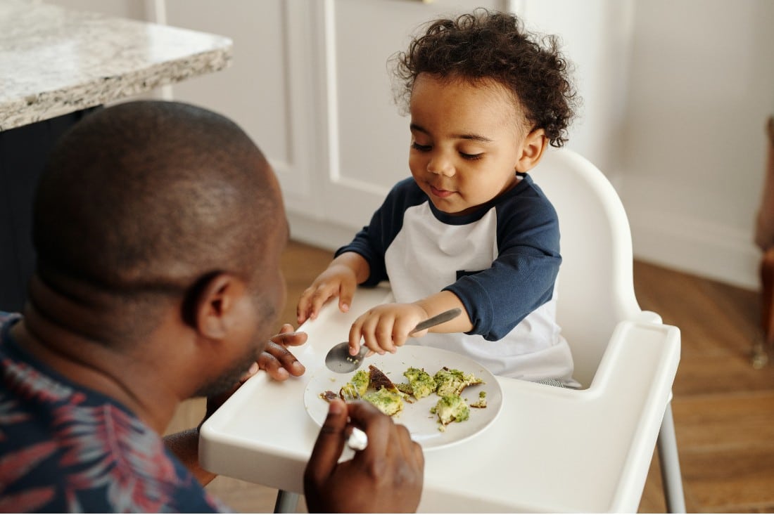 un papa qui donne à manger des légumes à son bébé
