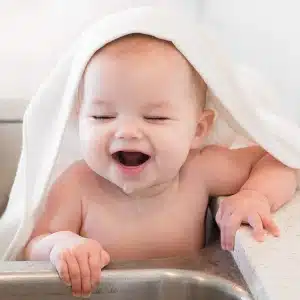 Ensemble de serviettes à capuche et de gant de toilette pour bébé avec un bébé qui rigole
