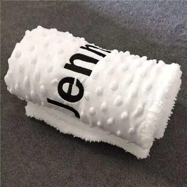 Couverture en microfibre enroulée blanche avec des lettres noires avec un fond gris