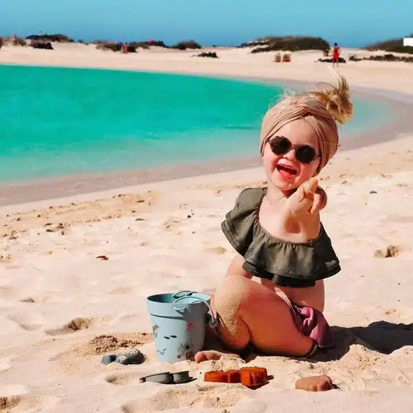 Ensemble de jouets de plage en silicone avec un fond une petite fille dans la plage