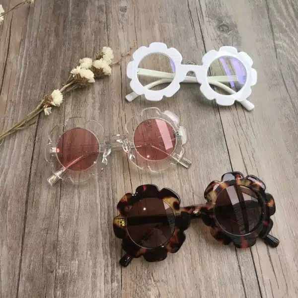 Lunettes de soleil pour bébé en forme de fleur à plusieurs coloris avec un fond en bois