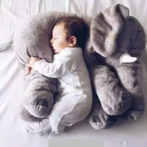 Oreiller en forme d'éléphant doux avec un bébé qui dort dans les bras de cet oreiller