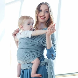 Une maman qui porte un porte-bébé souple avec pochette de rangement bleu