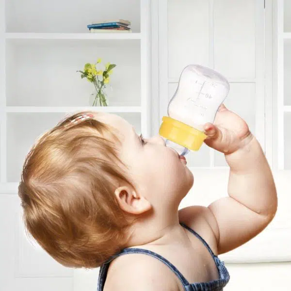 Un bébé qui boit dans le mini biberon d'allaitement naturel