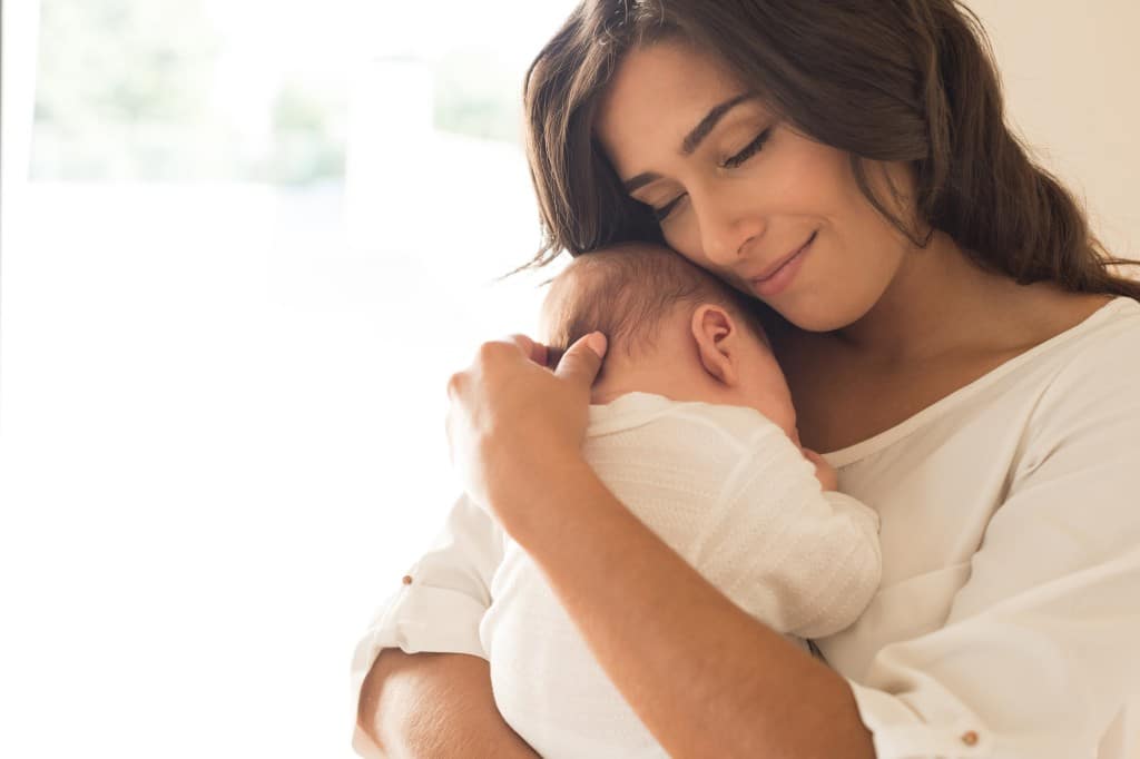 une jeune maman qui fait un câlin à son bébé