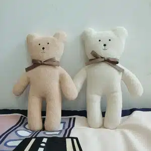 Deux mignons oursons en peluche pour bébé un blanc et un marron sur le lit