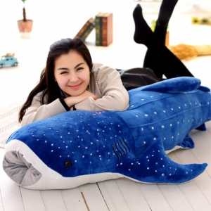 Requin en peluche de grande taille bleue avec une fille sur la peluche