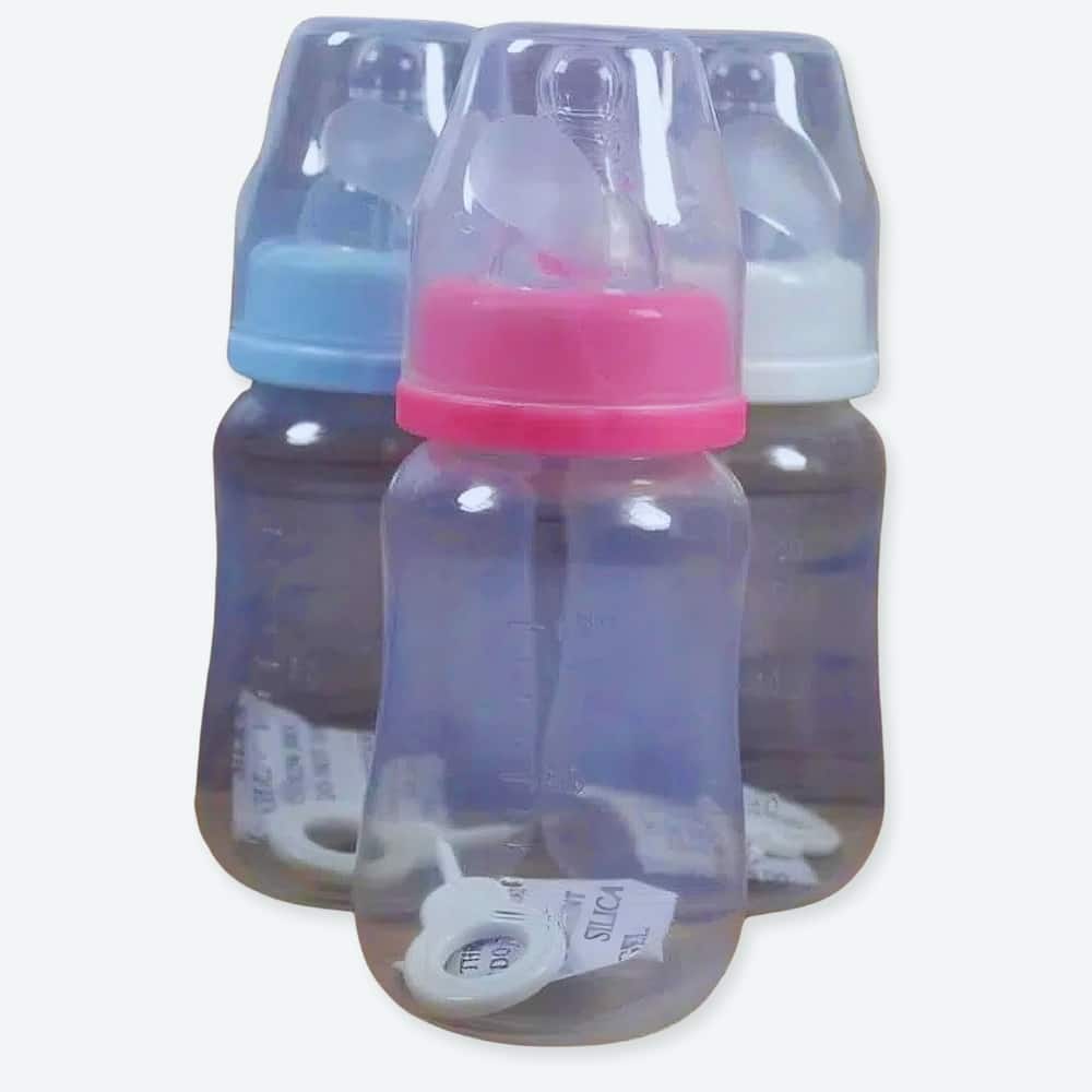 Biberon d'alimentation pour bébé un rose, un bleu et un blanc avec le fond en bois