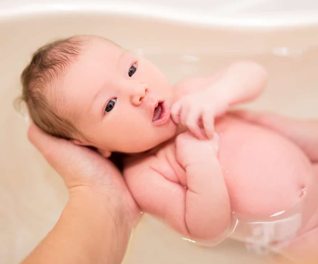 un bébé est en train de prendre son bain dans les mains d'un adulte
