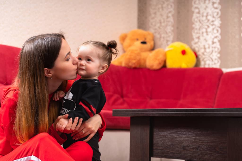 une maman serre sa fille dans les bras et l'embrasse sur la joue