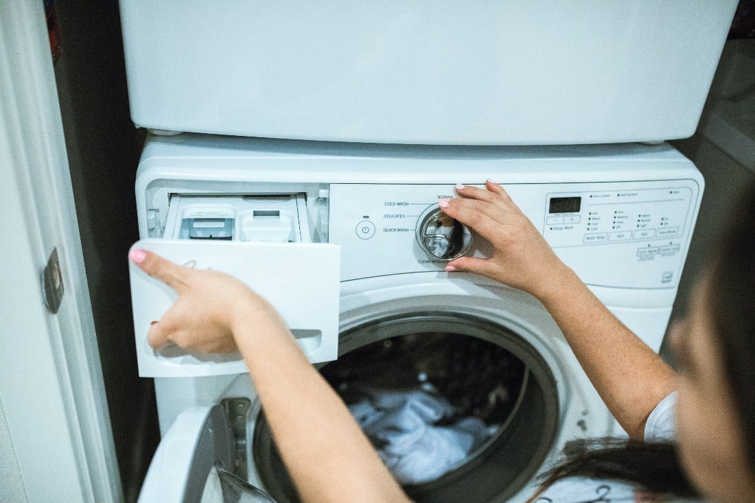 femme programmant une machine à laver le linge