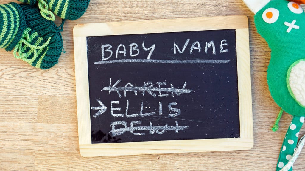 on voit une ardoise sur laquelle est écrit à la craie "Baby Name" Karen, Ellis, Deni. Les prénoms Karen et Deni ont été barrés.