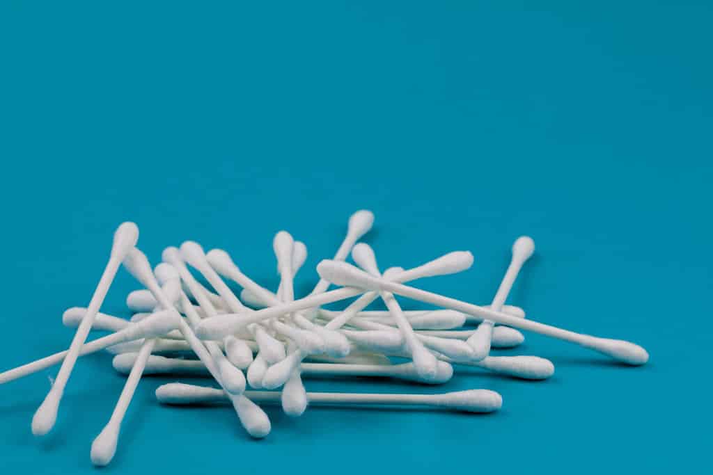 sur un fond bleu, plusieurs cotons-tiges sont disposés pêle-mêle