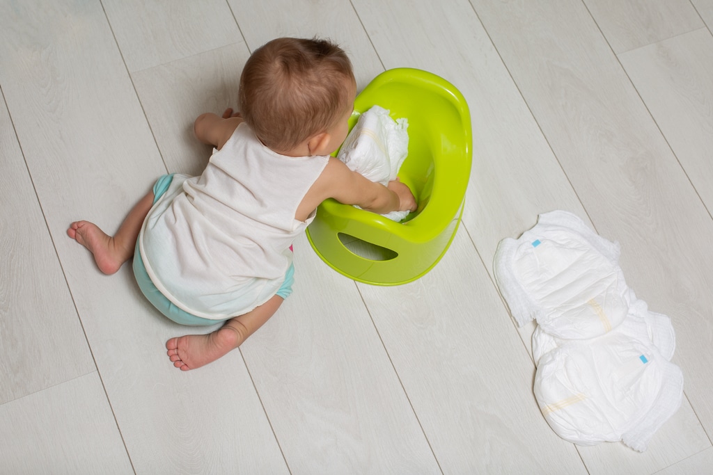 vue du dessus sur un bébé par-terre qui a mis des couches propres dans son pot vert