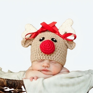 Chapeaux de noël en forme de cerf pour nouveau-né marron avec un bébé qui porte le chapeaux avec un fond en bois