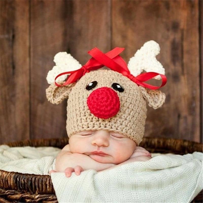 Chapeaux de noël en forme de cerf pour nouveau-né marron avec un bébé qui porte le chapeaux avec un fond en bois