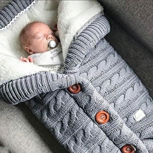 Couverture fourrée spécial hiver pour bébé gris avec un bébé qui dort dans la couverture douce