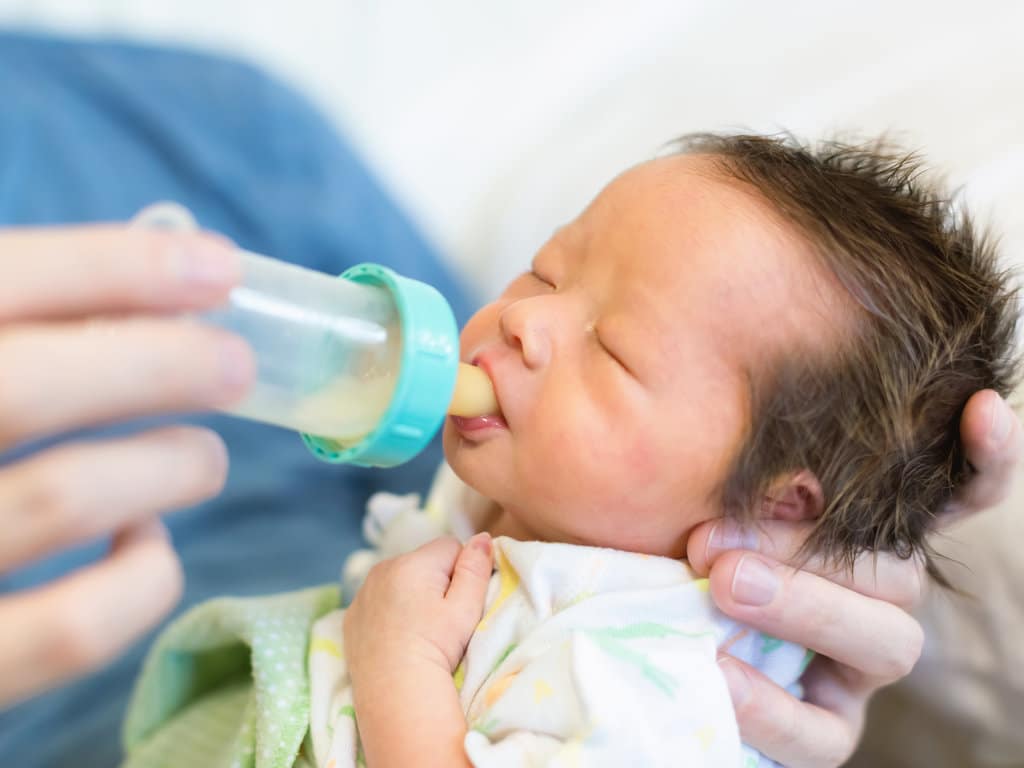 vue rapprochée sur un nouveau-né qui boit un biberon avec une tétine imitant le sein maternel