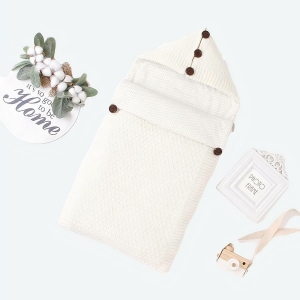 Sac de couchage blanc pour bébé collection hiver avec un fond blanc et des fleurs sûr le côté