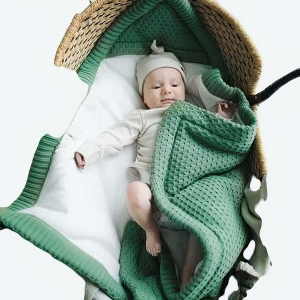 Sac de couchage collection hiver pour bébé vert avec un bébé qui dort sur le panier