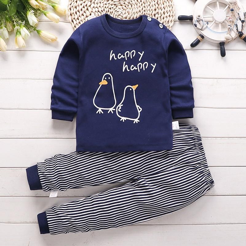 Pyjama bleu pour bébé avec pingouins avec un fond en bois blanc et des fleurs