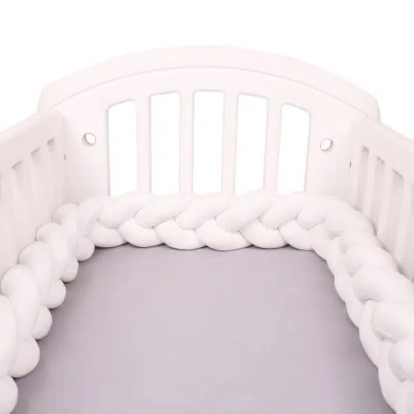Tour de lit tressé blanc dans un lit de bébé avec un fond blanc