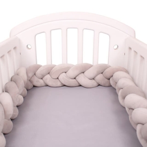 Tour de lit tressé gris dans un lit de bébé avec un fond blanc