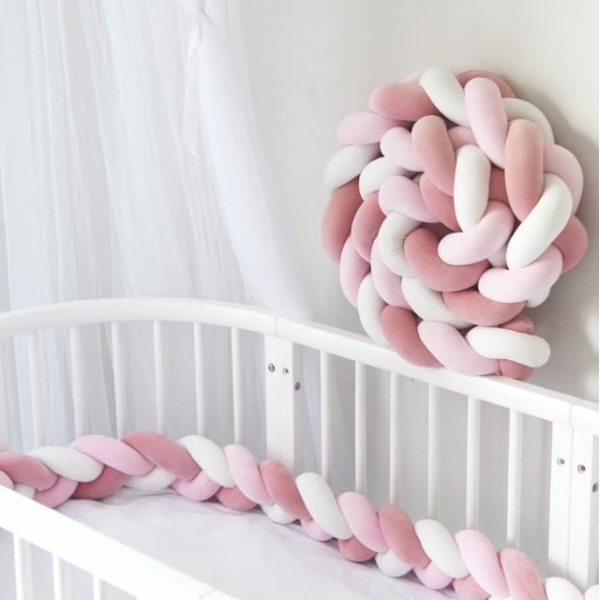 Tour de lit tressé rose et blanc dans un lit de bébé