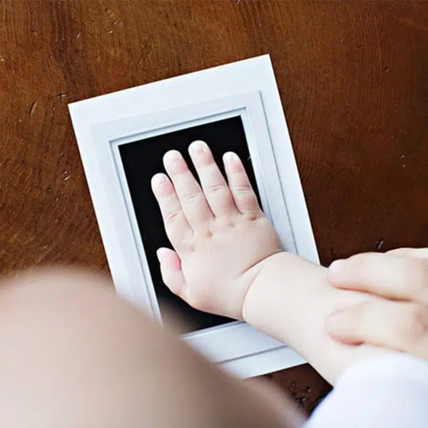 Kit d'empreintes à encre pour bébé avec un bébé qui met sa main dans le kit
