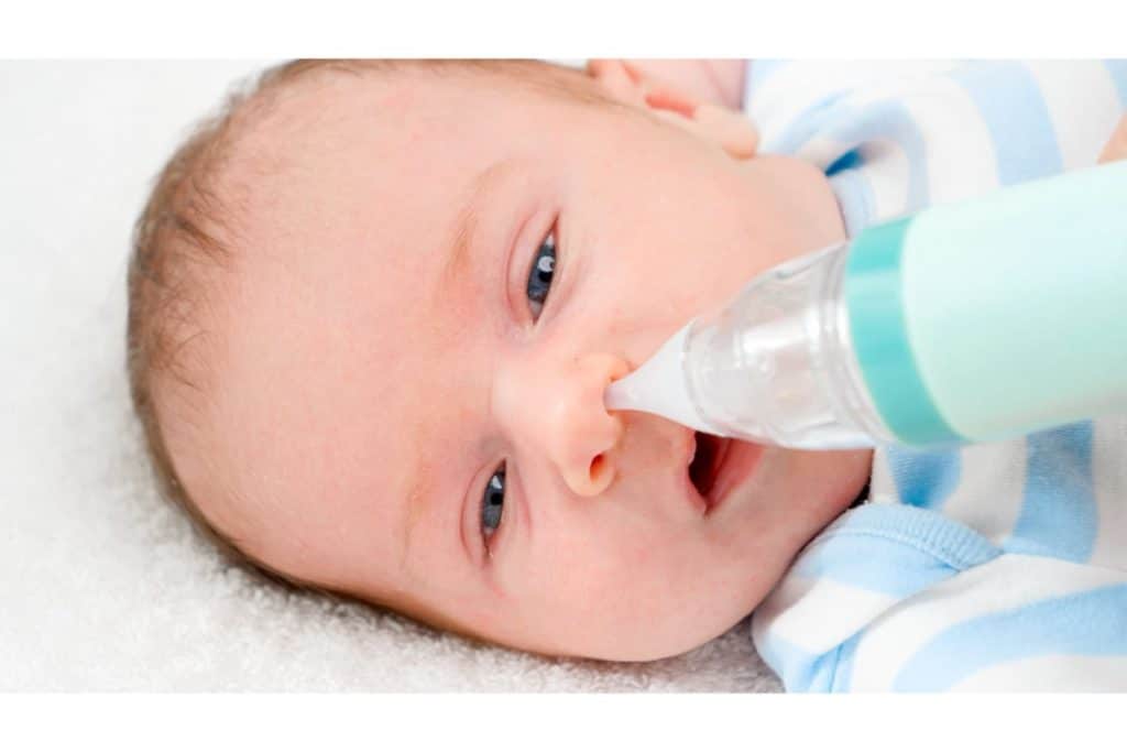 vue rapprochée d'un bébé allongé avec un mouche bébé dans le nez