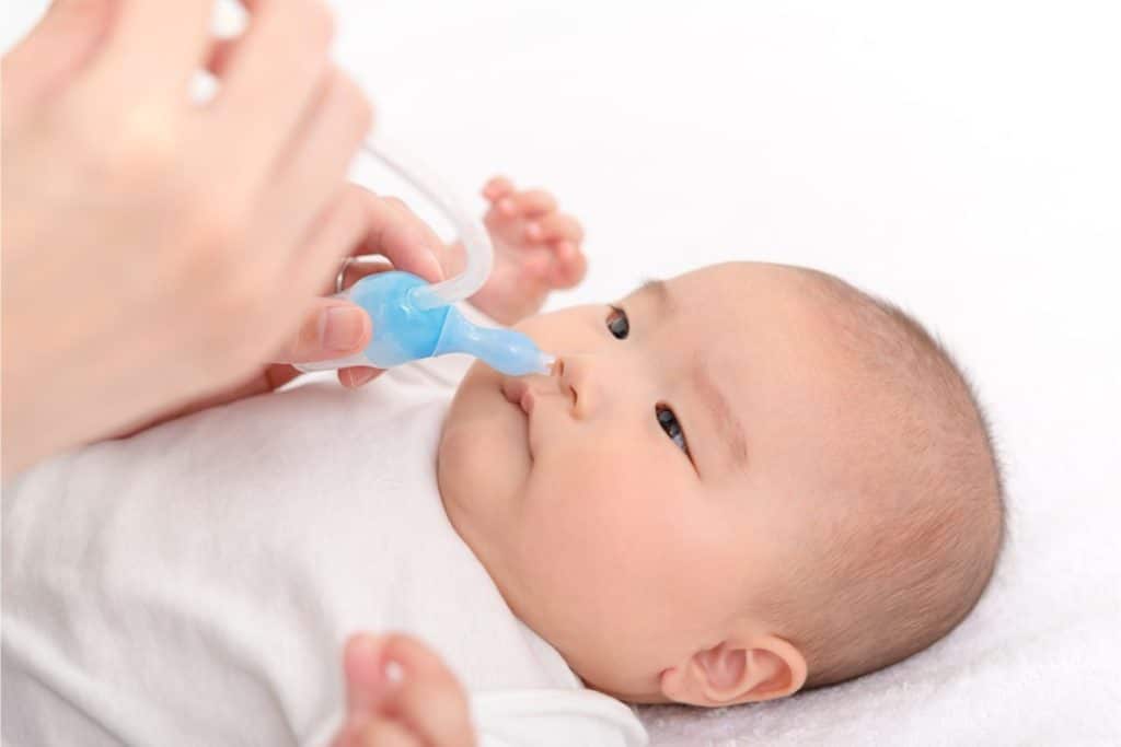 un bébé asiatique allongé a un mouche bébé dans le nez