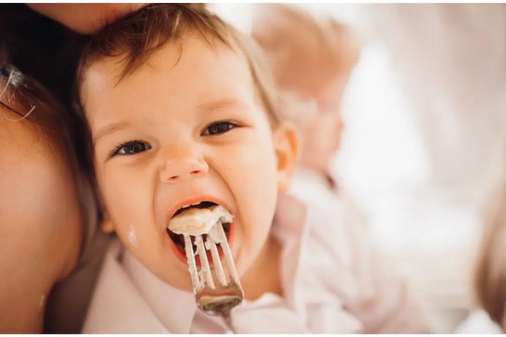 plan rapproché sur un enfant a la bouche grande ouverte qui accueille une fourchette avec un morceau de nourriture.