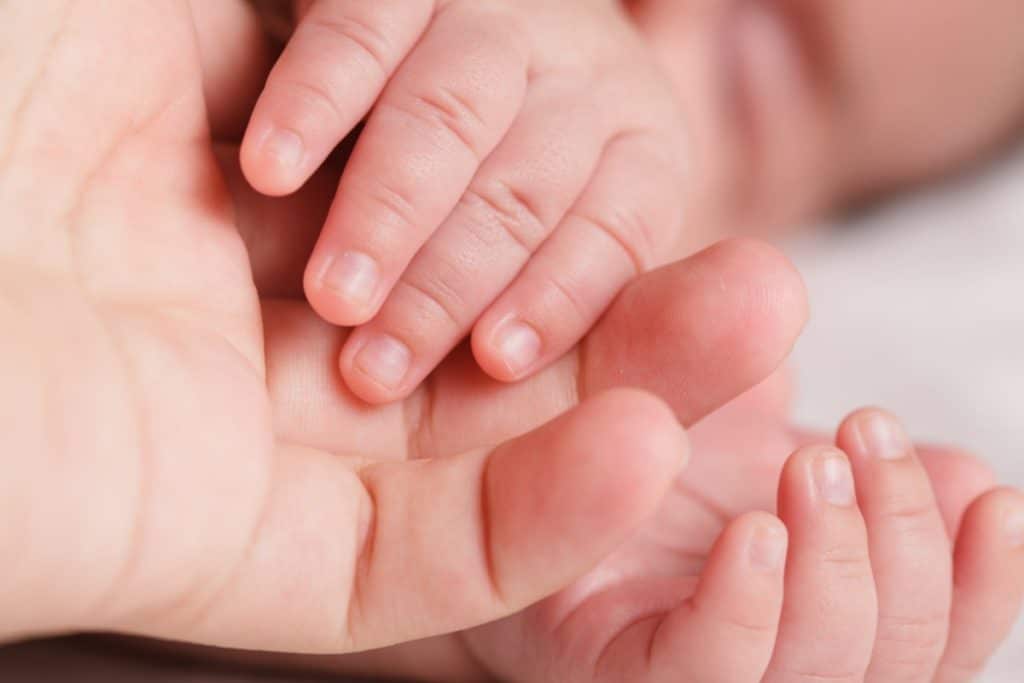 vue rapprochée d'une main de bébé sur des mains d'adulte