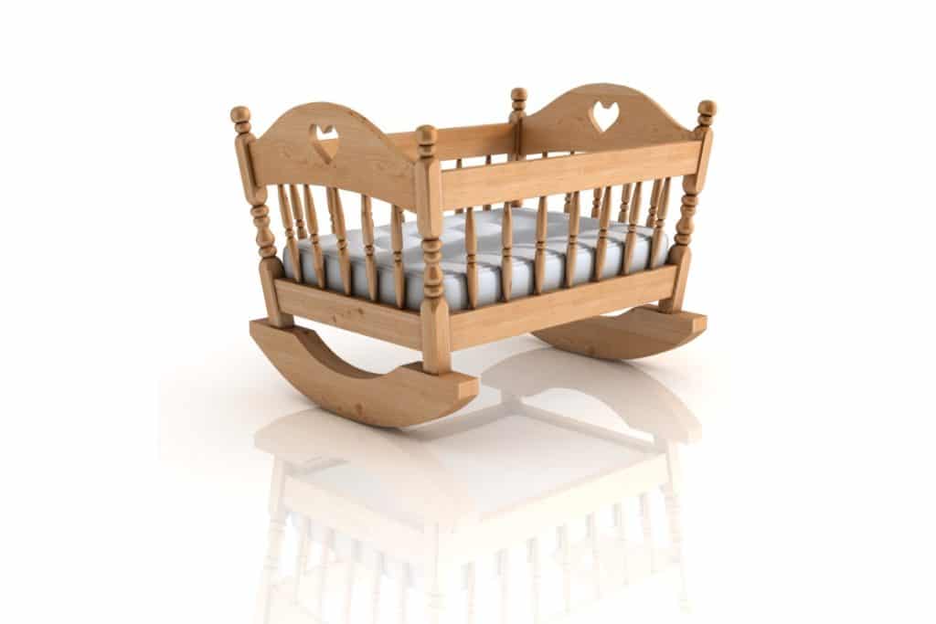 photo d'un berceau sur fond blanc avec un reflet au sol du berceau. c'est un berceau à bascule qui peut se basculer de droite à gauche.