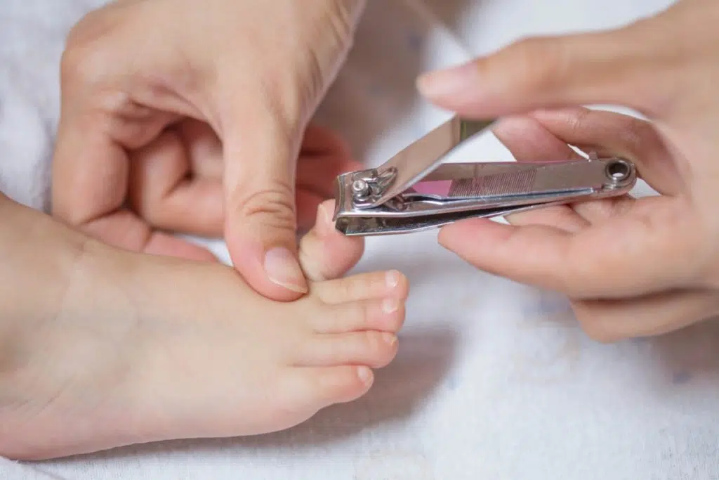 vue rapprochée de mains d'adulte utilisant un coupe ongles sur un petit pied d'enfant