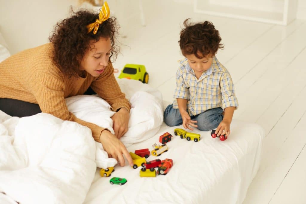 une maman et son fils jouent aux petites voitures sur le sofa