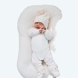 Petit bébé endormi et installé dans un réducteur de lit