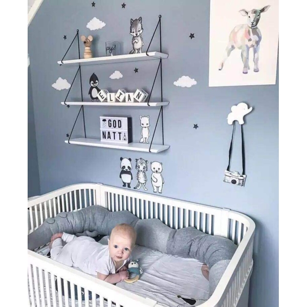 dans une chambre d'enfant se trouve un lit pour bébé et un nourisson installé dedans avec un tour de lit crocodile gris