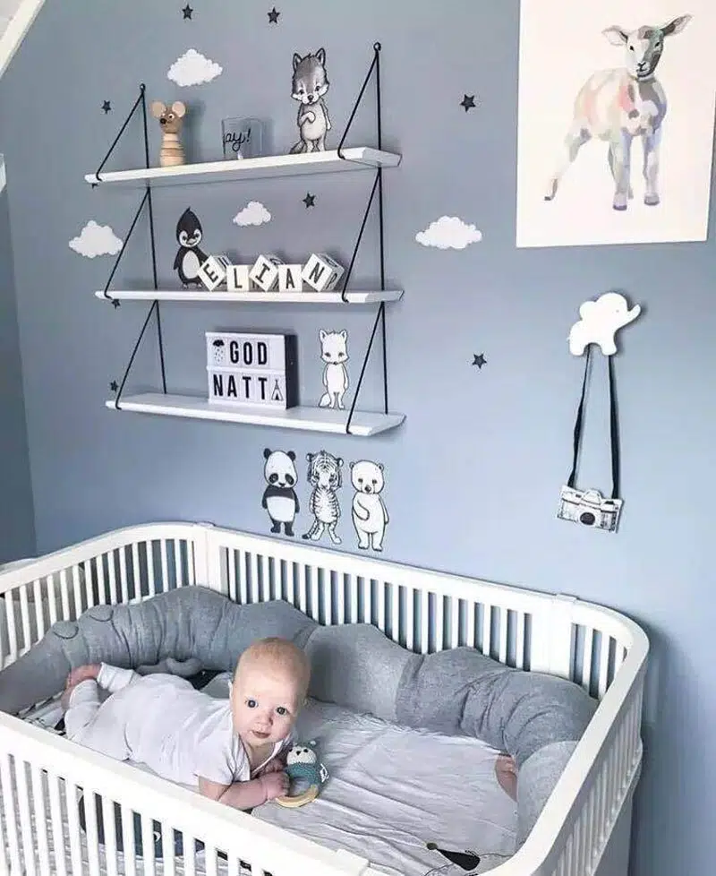 dans une chambre d'enfant se trouve un lit pour bébé et un nourisson installé dedans avec un tour de lit crocodile gris